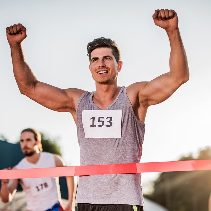Young happy man celebrating his success after crossing the finish line and winning the race.