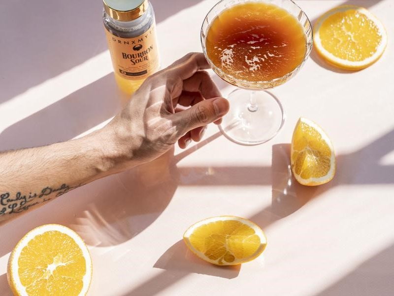 A hand reaching out for a glass of cocktail.