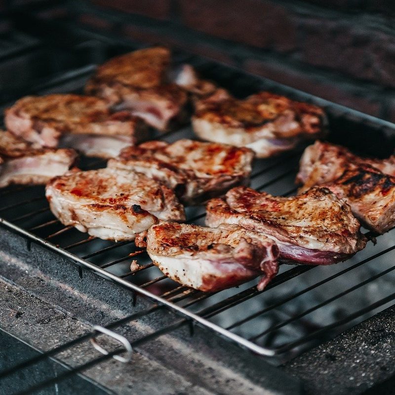 Pork being grilled over charcoal