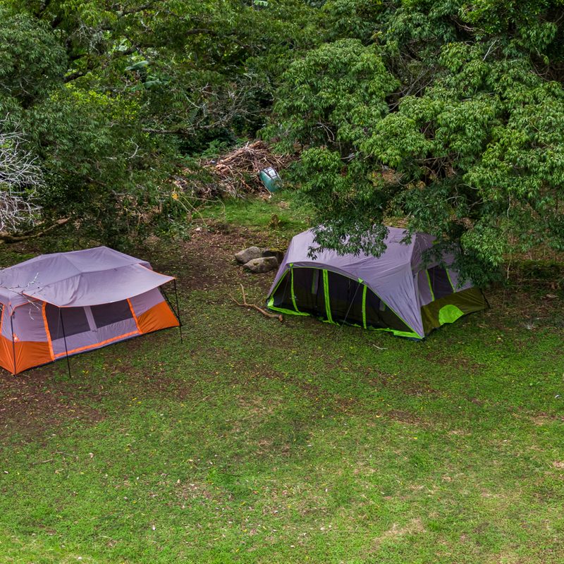 A bird's eye view of two tents in the middle of a forest.
