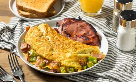 Homemade omelette on plate next to toast and orange juice.