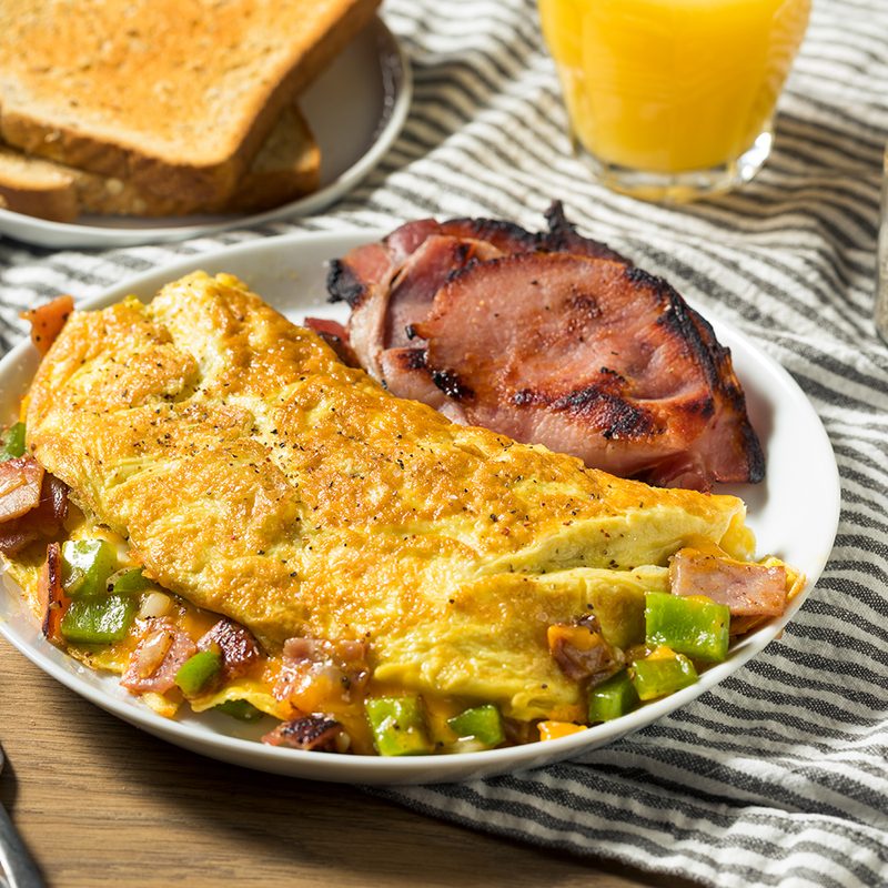Homemade omelette on plate next to toast and orange juice.