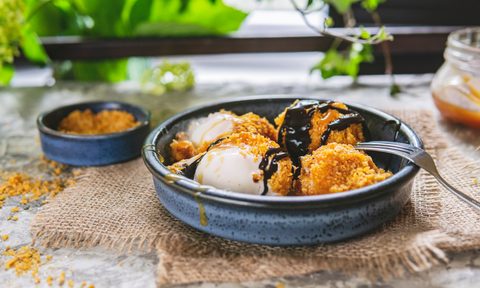 Fried white ice cream on blue plate, grey table with flowers near window.