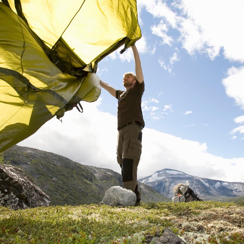 A man preparing to pitch his tent on a mountain.