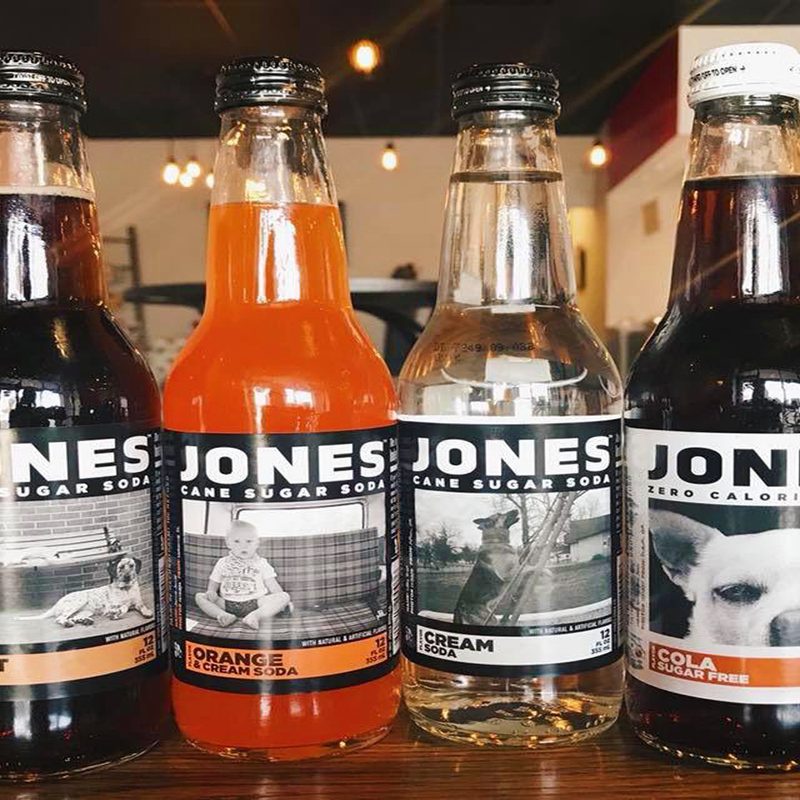 Four bottles of Jones Canes Sugar Soda on a wooden table at Ignite Coffee & Tea.