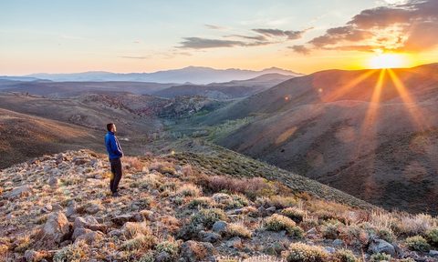 A person standing on a hill alone at sunset