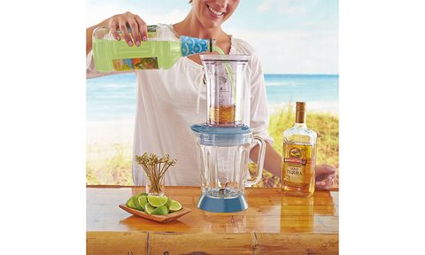 Margaritaville Key West Frozen Concoction Maker placed on a table outside with someone pouring a drink into it.