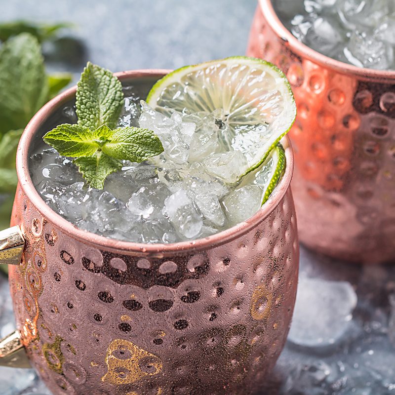 Moscow mule drinks in copper mugs garnished with lime and mint