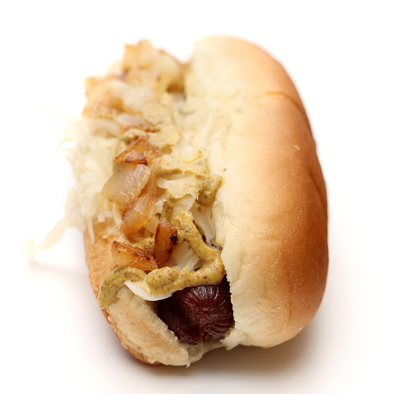 A hot dog with white onions, mustard, and sauerkraut on a white background