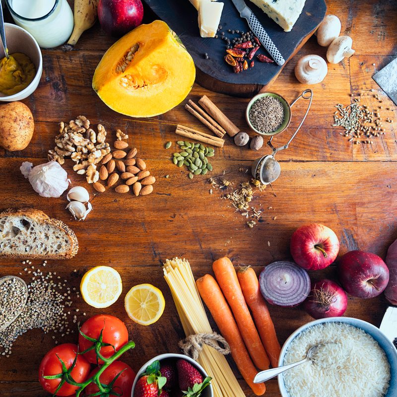 Colorful and healthy table composed with fruits and vegetables of many different types, meat, cheese, eggs, fish, spices and grains on wooden rustic table, view from above.