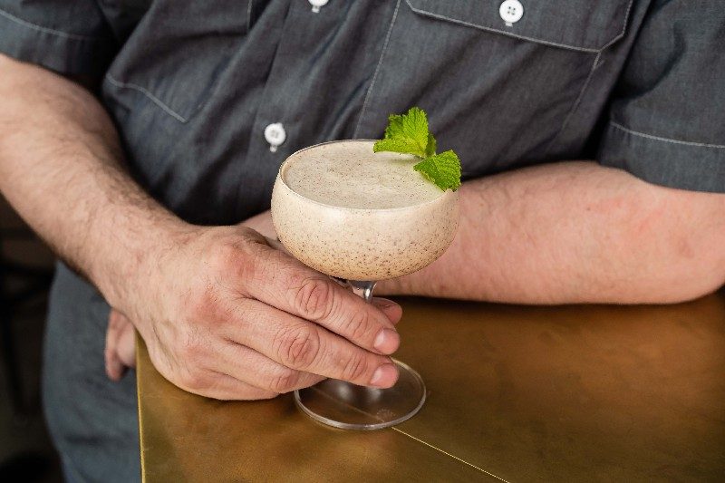 Ice cream cocktail, Not Your Grandma's Grasshopper, in a martini glass held by a man.