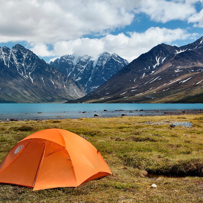 An orange tent in the middle of the wilderness.
