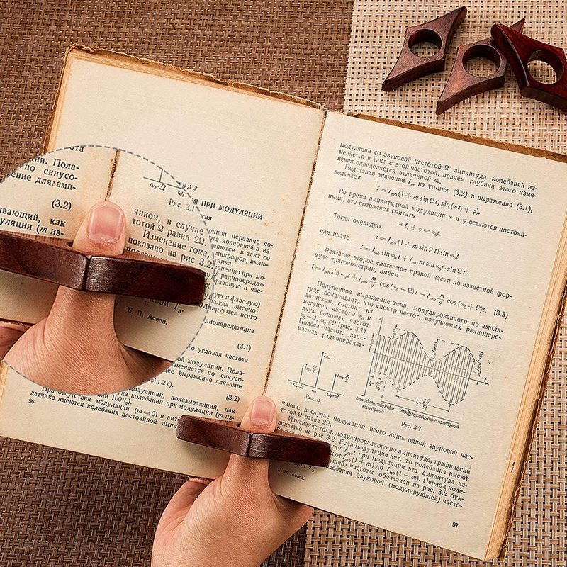 A finger holding a book with an Outus Wooden Page Holder.