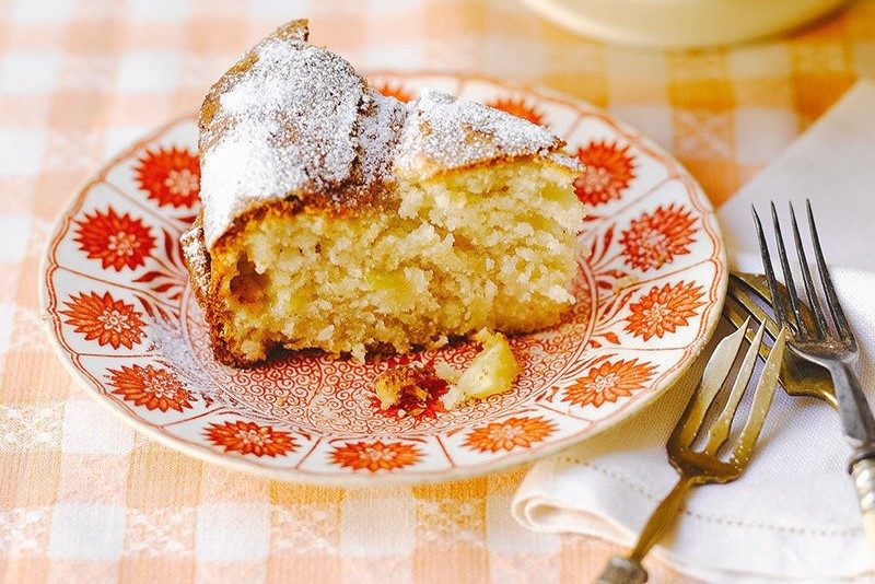 A slice of pineapple and coconut cake served on a red plate.