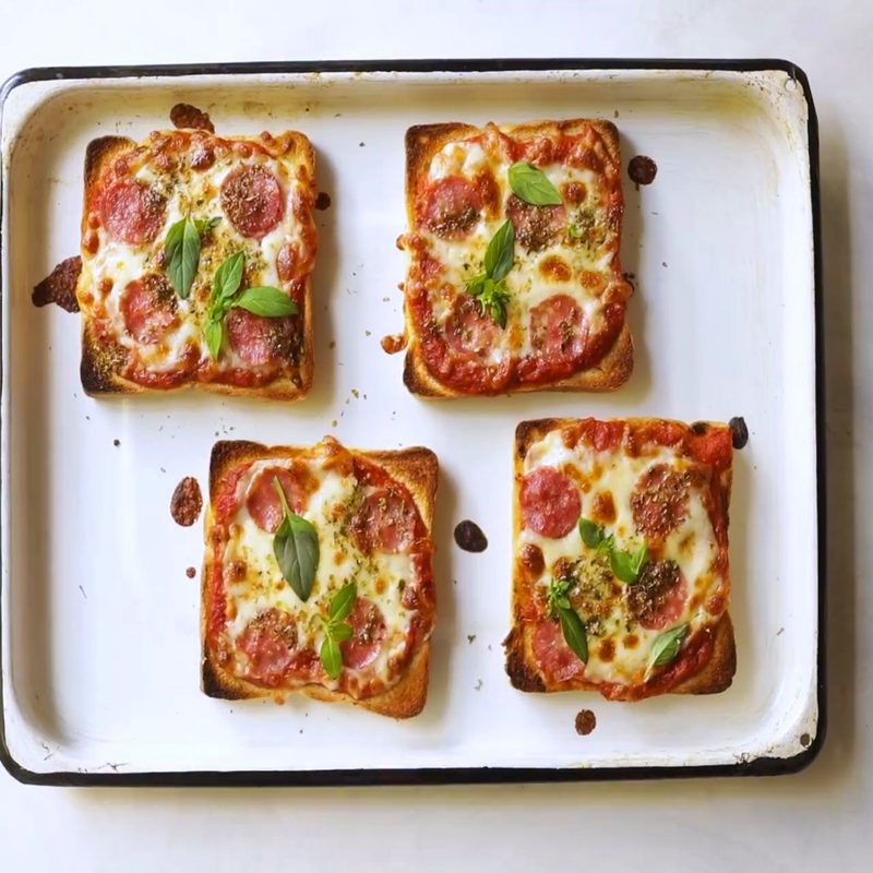 Four loaves of pizza toast on a tray.