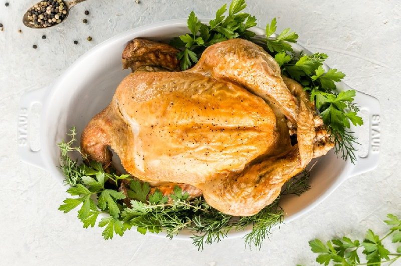 a whole roasted chicken in serving dish.