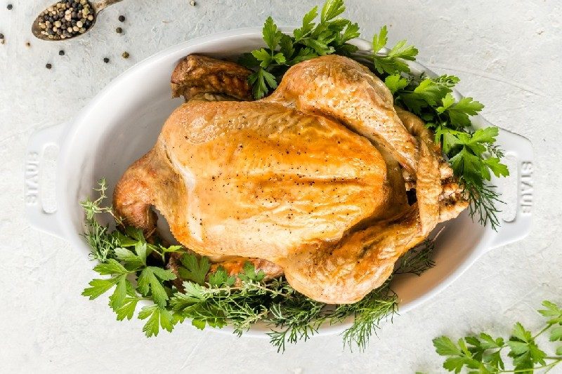 A whole roasted chicken in serving dish.