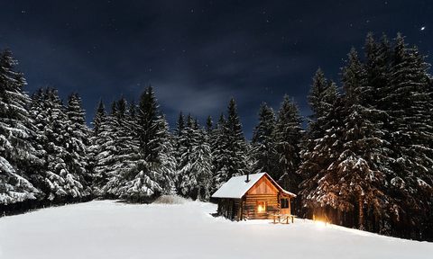 snowy cabin in the woods at night