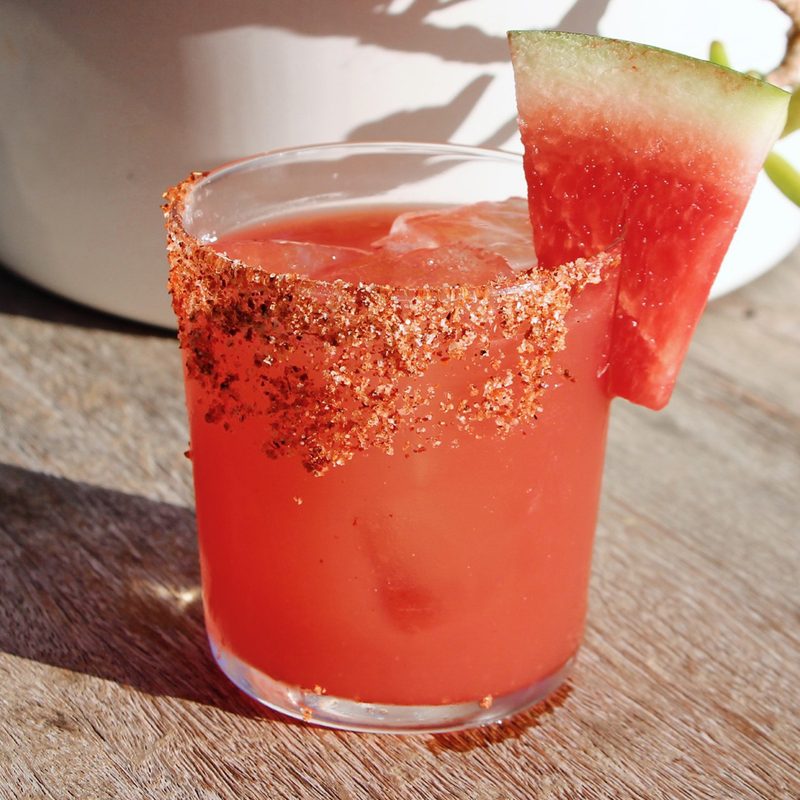 A glass of Spicy Cucumber Watermelon Margarita on a wooden table.