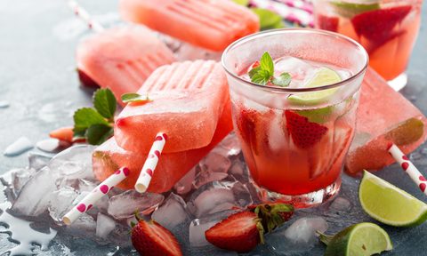 Strawberry mojito popsicles with a glass of it on the side.