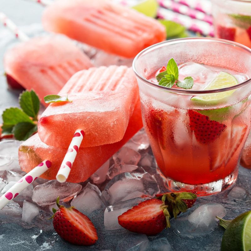 Strawberry mojito popsicles with a glass of it on the side.