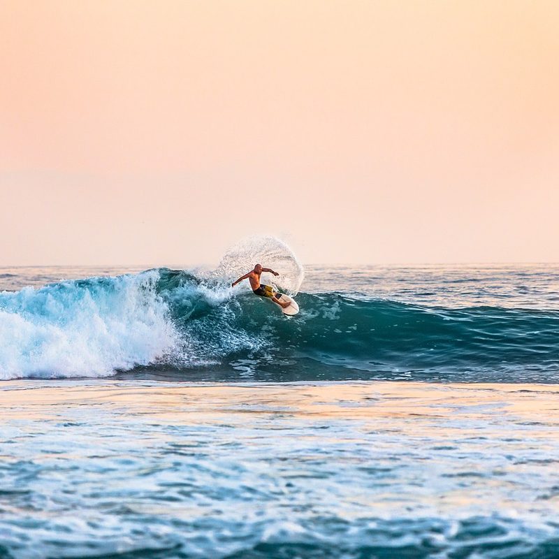 surfer at sunset riding a crashing wave.