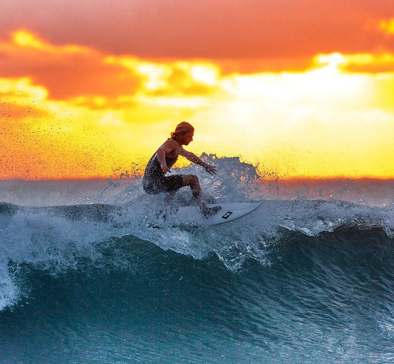 surfer riding short wave as the sun is setting.