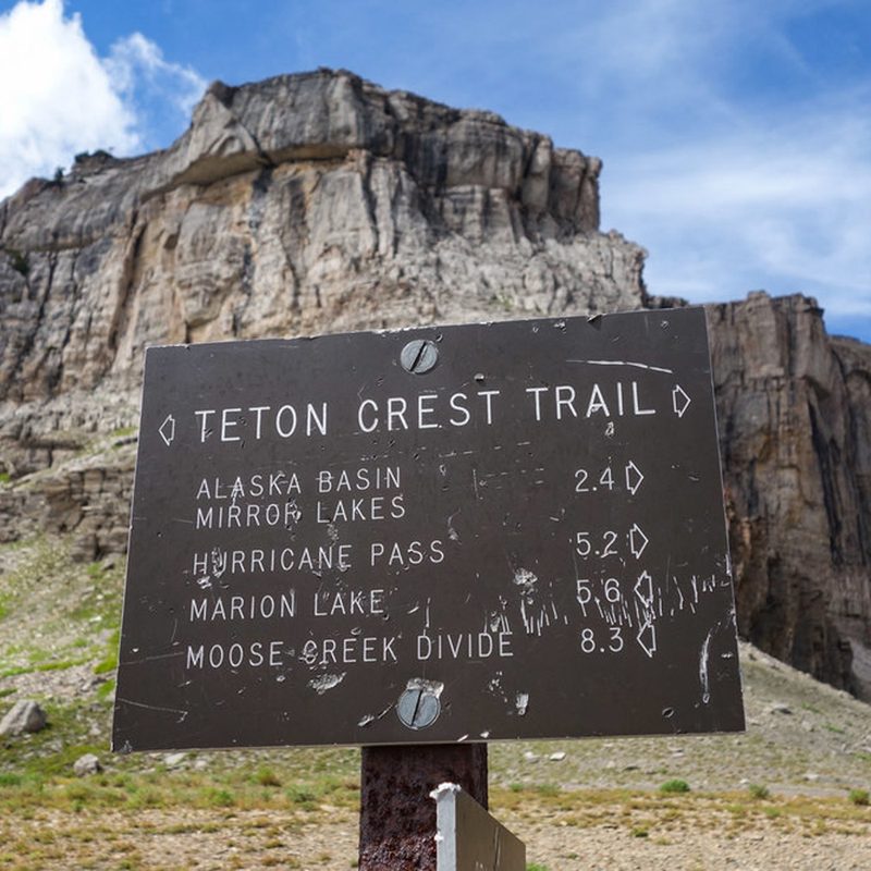 A sign board in Teton Crest Trail that says Alaska Basin, Mirror Lakes, Hurricane Pass, Marion Lake, and Moose Creek Divide.