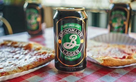 Can of Brooklyn Lager beer in between two slices of pizza.