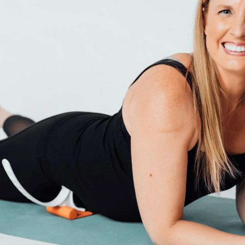 A woman using the Hip Hook on an exercise mat.