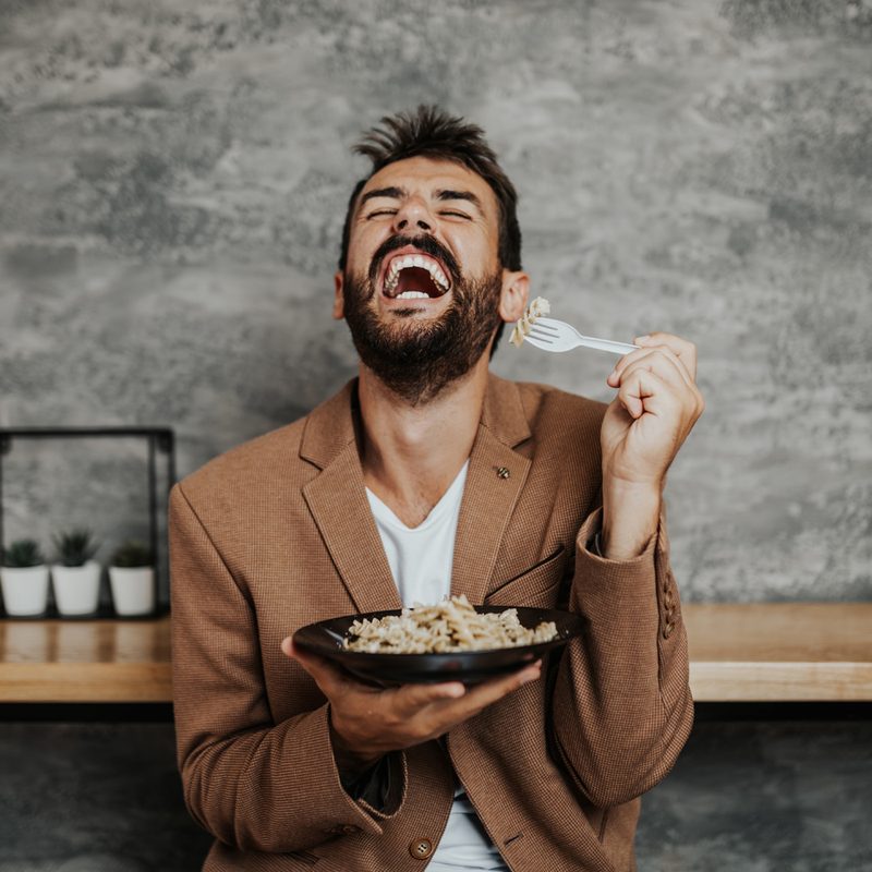 A man happily eating food in a restaurant.