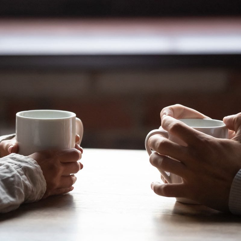 Two people on a date, holding their mugs.