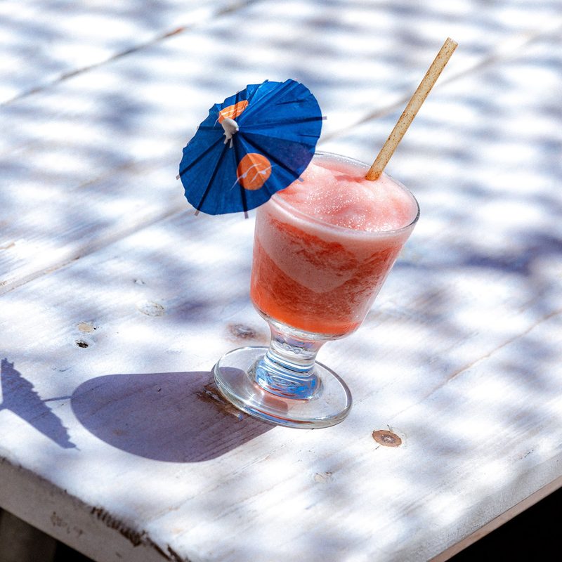 A glass of Watermelon Frozé on a white table.
