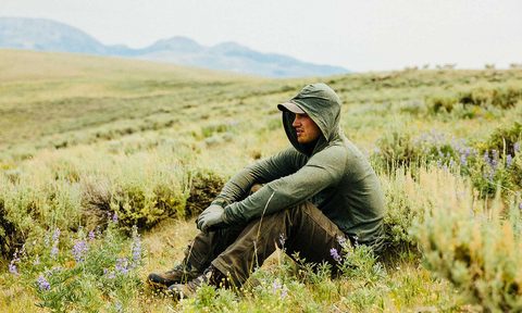 A man sitting in the fields wearing a jacket.