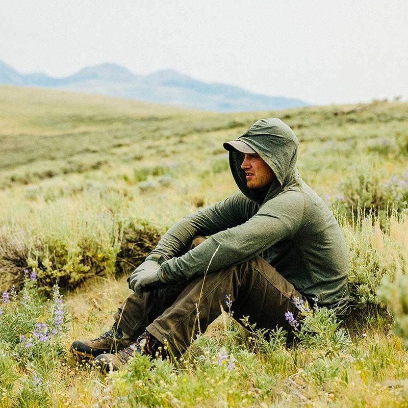 A man sitting in the fields wearing a jacket.