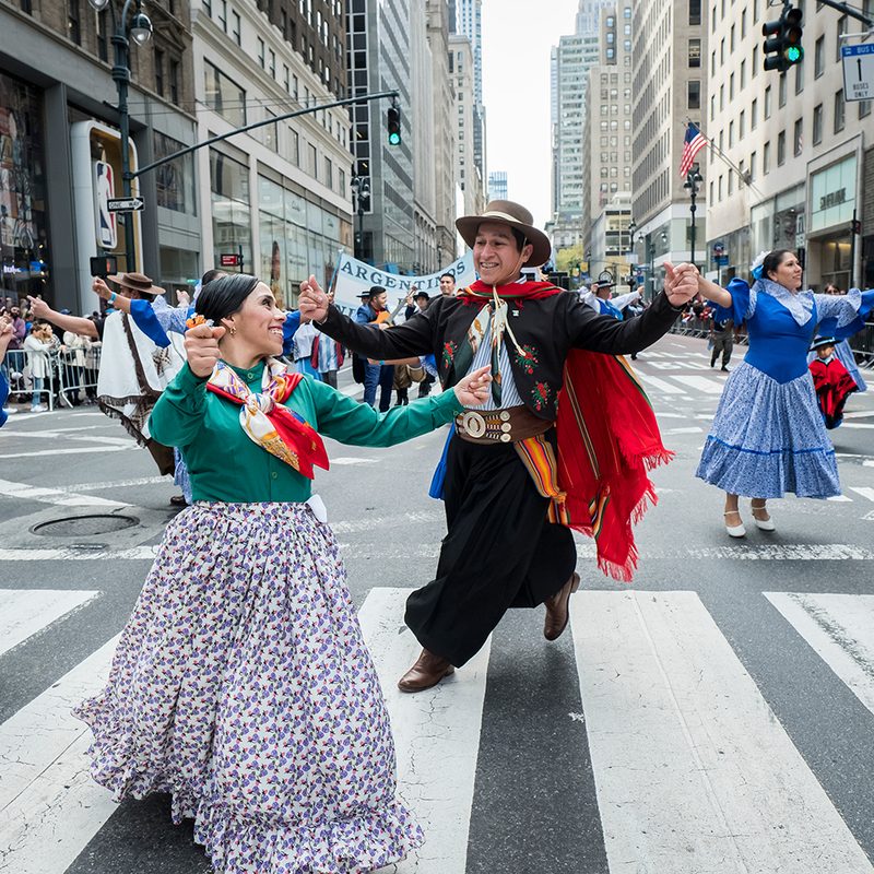Marchers dance together down 5th Avenue in traditional costumes during the 55th Hispanic Day Parade.