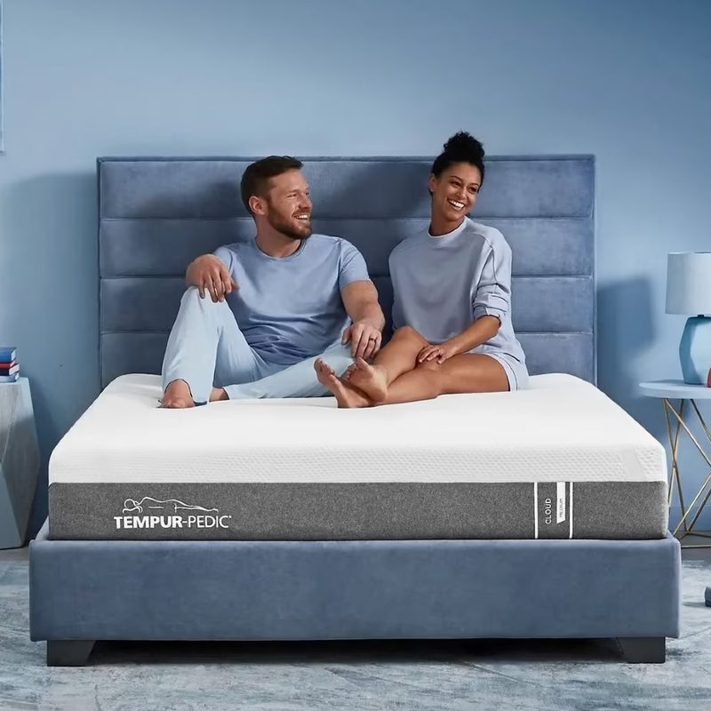 A couple sitting on a Tempur-Pedic Tempur-Cloud Mattress.