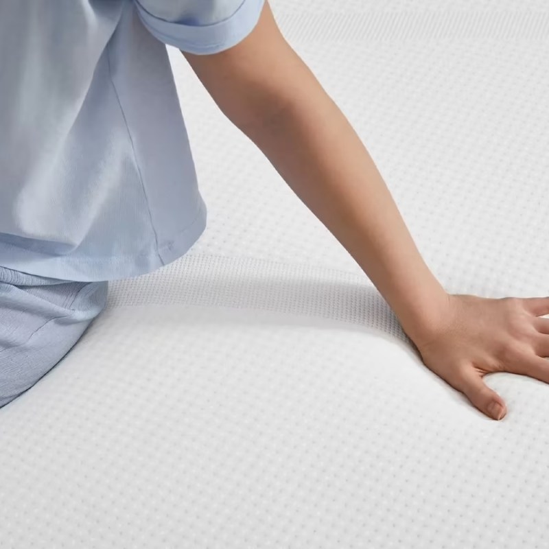 A woman sitting on a Tempur-Pedic Tempur-Cloud mattress.
