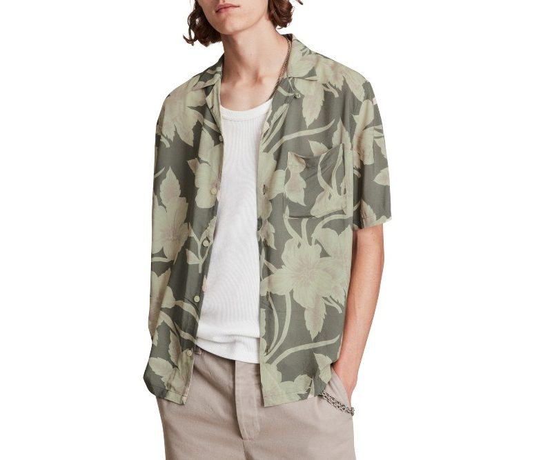 A man with his hands in his pockets is wearing a floral shirt from AllSaints.