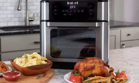 Ninja Air Fryer Oven with plates of food next to it in kitchen.