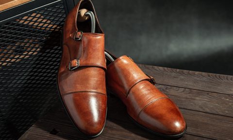 An elegant pair of leather monk strap shoes on a wooden table.