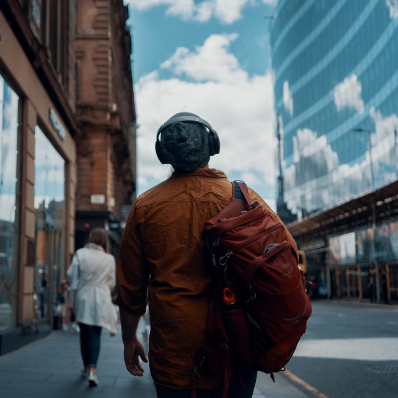 Man walking a city with the best headphones for travel.