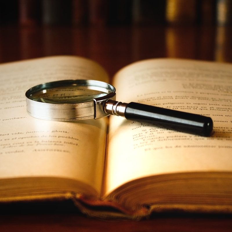 A magnifying glass on old book, under a warm light.