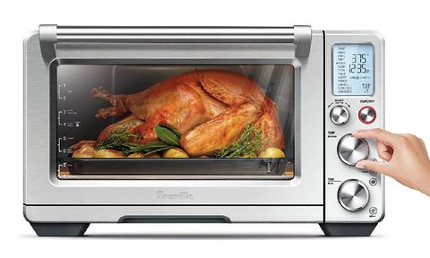 Woman cooking a whole turkey in air fryer oven.