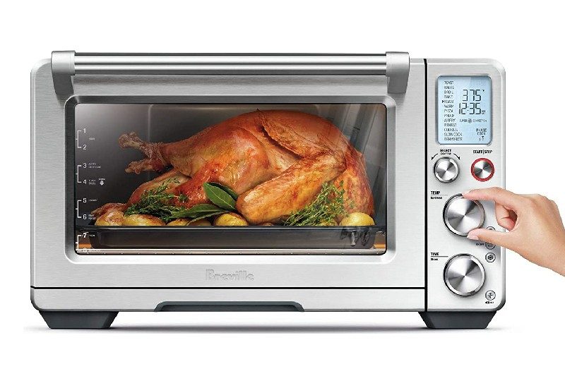 Woman cooking a whole turkey in air fryer oven.