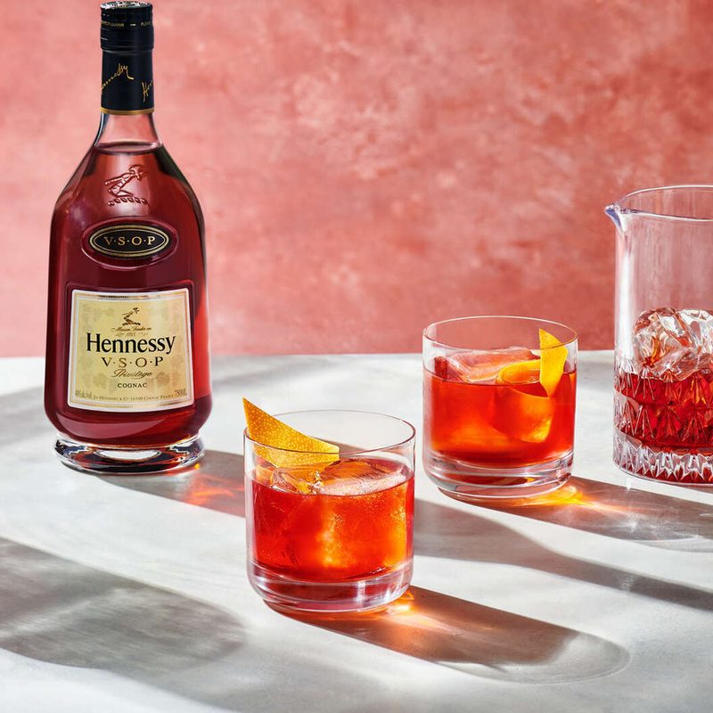 A bottle of Hennessy VSOP Cognac beside two glasses and a pitcher.