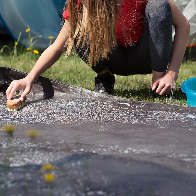 Cleaning groundsheet of a camping tent.
