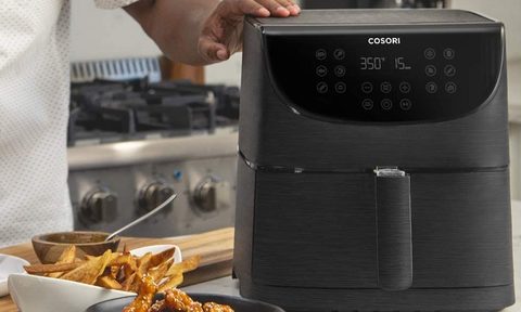 COSORI Air Fryer Max XL on counter with chef cooking.