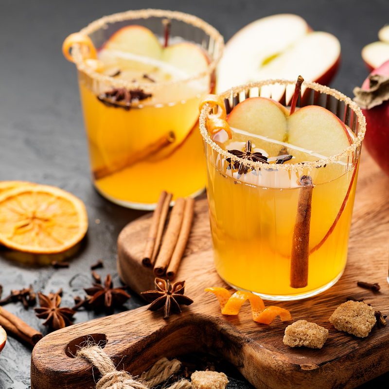 Hard apple cider spiced cocktail with sliced red apples, cinnamon, cardamom and star anise.