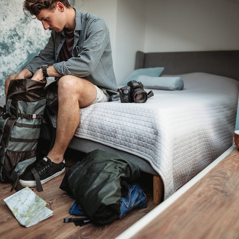 A man rummaging through his backpack in a room.